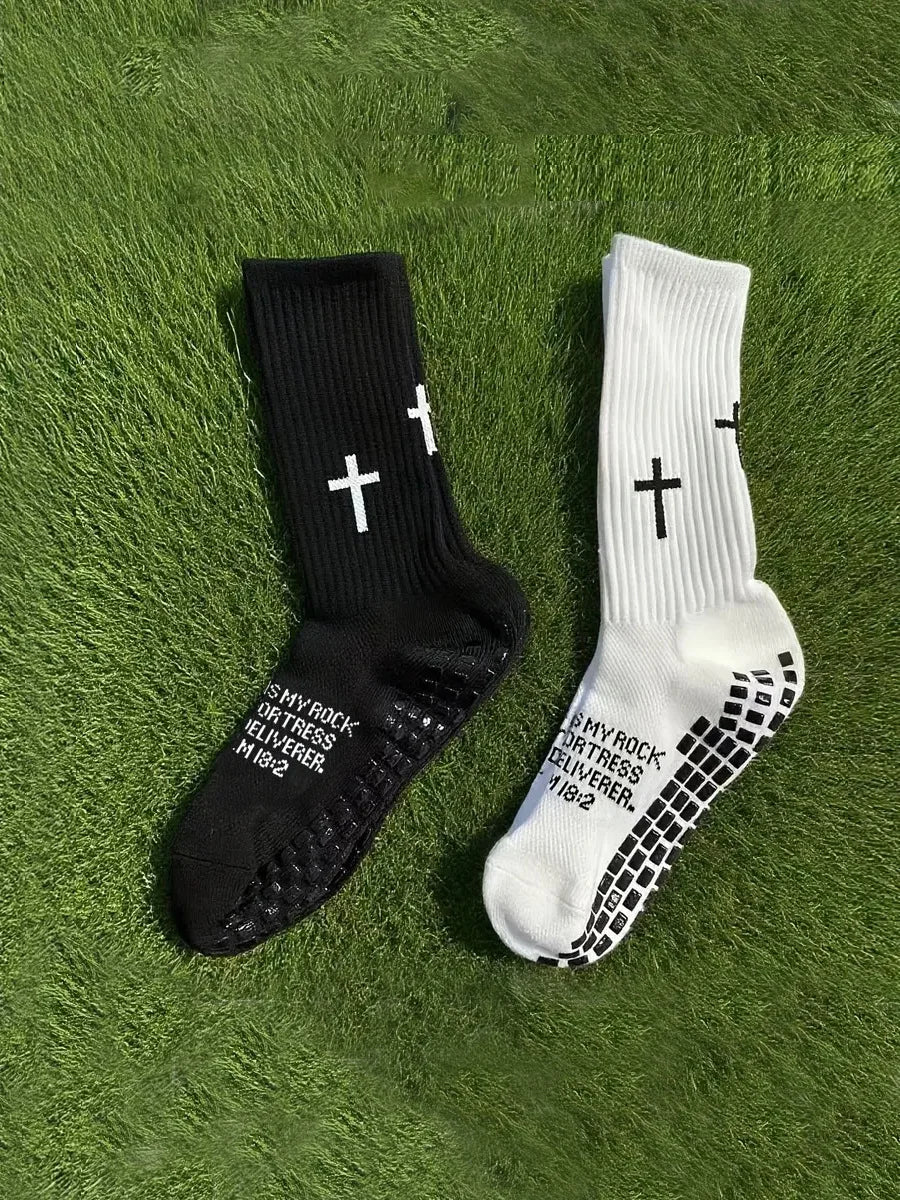 A pair of black and white cross printed athletic socks lying on green grass.