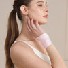 A woman wearing a pink ultra-thin spandex wrist guard for joint support on her arm.