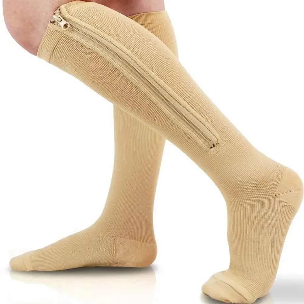 A close-up of beige compression socks with a zippered ankle opening.