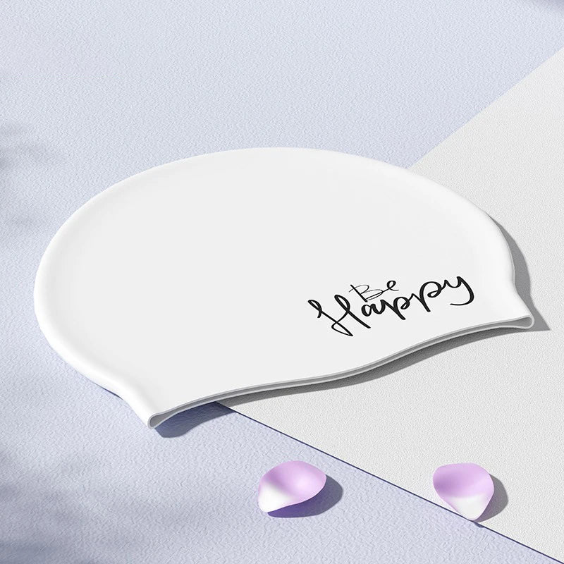 Gorra de natación de silicona blanca con la palabra Happy, apoyada sobre una superficie clara.