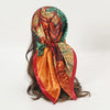 An elegant satin square scarf featuring an abstract pattern of orange, green, and rust tones.