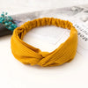 A mustard yellow bohemian chiffon headband tied in a knot, resting on white paper.