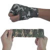 Una mano sostiene una venda elástica de camuflaje envuelta en un brazo.