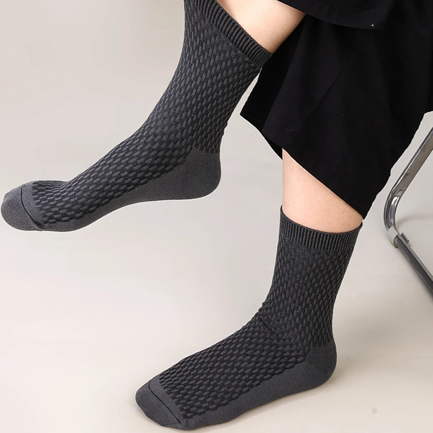 A close-up of a person wearing black bamboo fibre anti-odor socks on their foot.