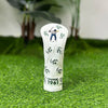 A white golf club head cover featuring a silhouette of a golfer and the text CHANGE 1961, placed on green grass.