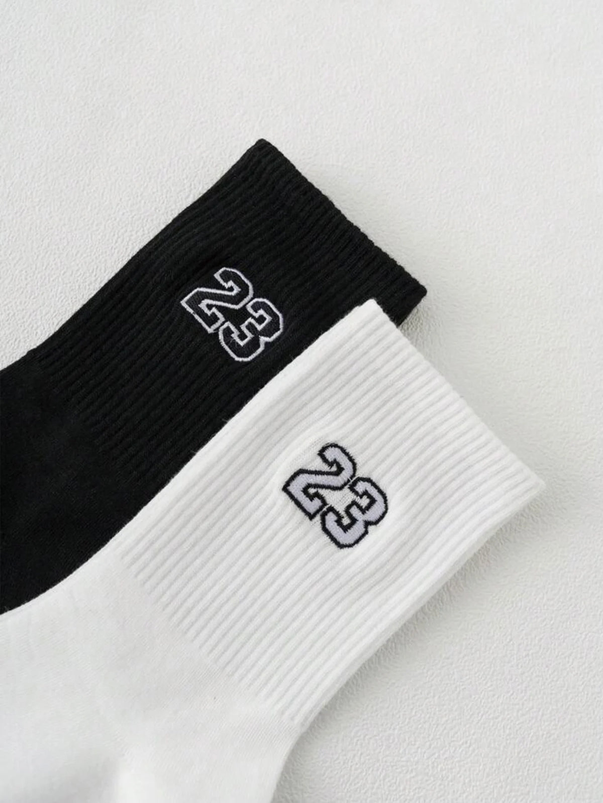 A pair of black and white men's classic crew socks with the number 23 printed on them.