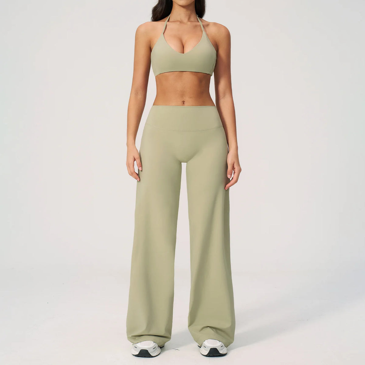 A woman wearing a light olive green women's premium fitness tracksuit top and matching pants.