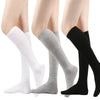 Un conjunto de medias hasta el muslo para mujer en colores blanco, gris y negro mostrados en una pierna.