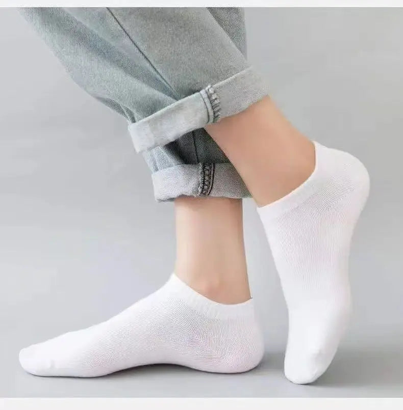 Calcetines náuticos blancos casuales y transpirables puestos en un pie contra un fondo gris claro.