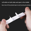 A hand is peeling off a piece of white double-sided fashion adhesive tape to reveal the sticky layer.