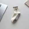 A pair of cream-colored yoga socks with black polka dots and a small embroidered heart on the toe.