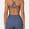 A woman wearing a navy blue high-support sports bra and matching leggings, shown from the back.