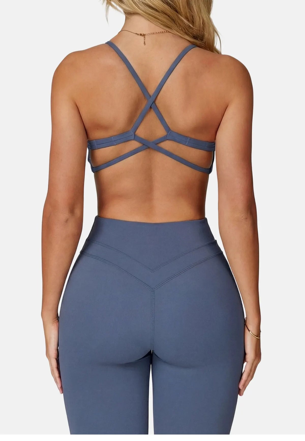 A woman wearing a navy blue high-support sports bra and matching leggings, shown from the back.