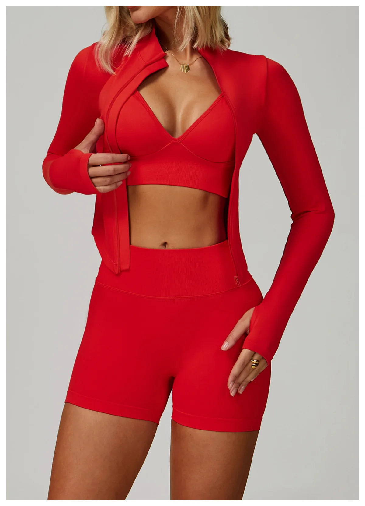 Eine Frau trägt ein rotes, nahtloses Sport-Yoga-Set mit langärmeligem Crop-Top und passenden Shorts.