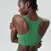 A model wearing a bright green high-impact stretch yoga crop top and matching bottoms, shown from the back.
