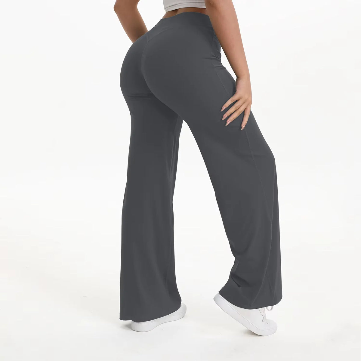A person wearing dark gray NCLAGEN SoftMotion straight leg yoga pants standing and looking down.