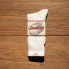 A pair of white tube socks featuring a graphic design with the word Quality on a beige background.
