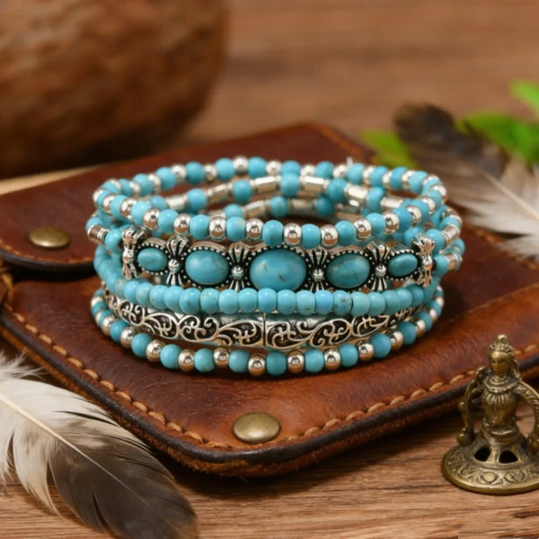 A stack of five bohemian turquoise beaded bracelets on a brown leather card with a feather.