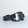 Black sport-grade skiing goggles with a black strap and clear lenses resting on a light surface.
