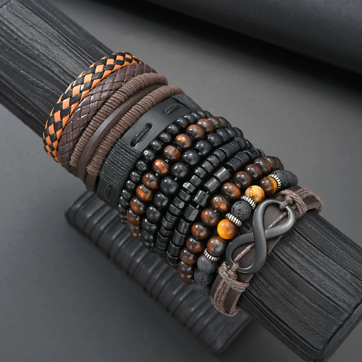 A close-up of a dark leather bracelet featuring multiple strands of black and brown beads and cord.