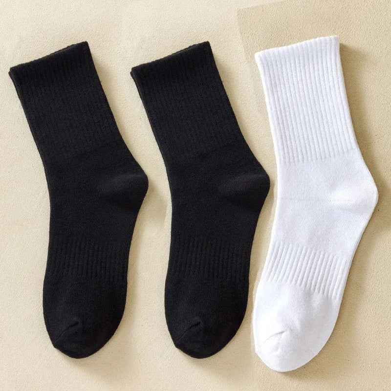 Une paire de chaussettes pour hommes en coton mélangé noir et blanc, posées sur un fond clair.