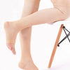 A pair of beige compression thigh-high socks worn on a white stool.