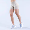 A person wearing beige seamless high-waisted yoga shorts and light blue athletic shoes.