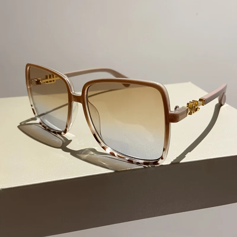 Retro two-tone gradient sunglasses with light brown frames and tinted lenses resting on a white surface.