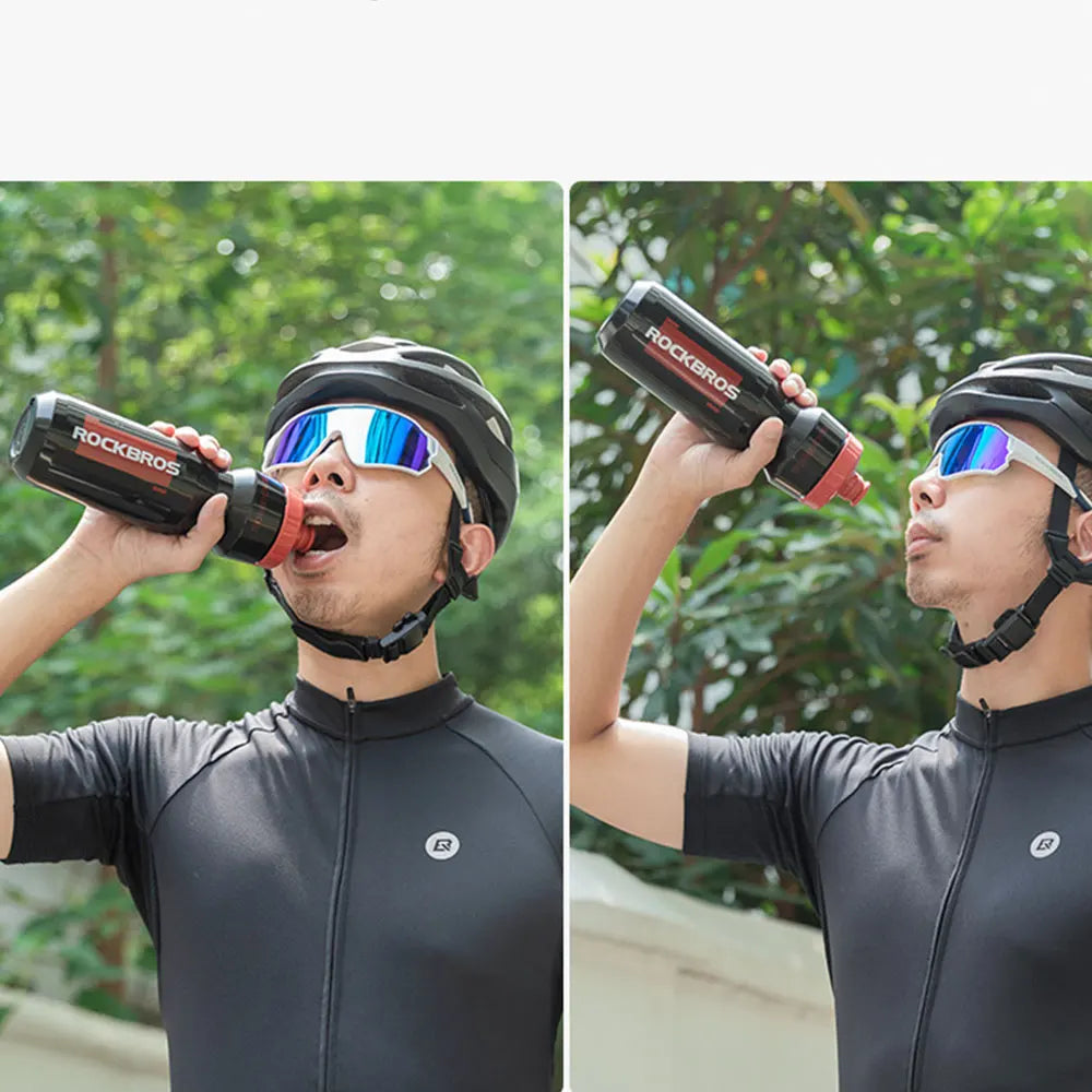 A man is using a black plastic sports water bottle to drink while wearing a black helmet and sunglasses outdoors.