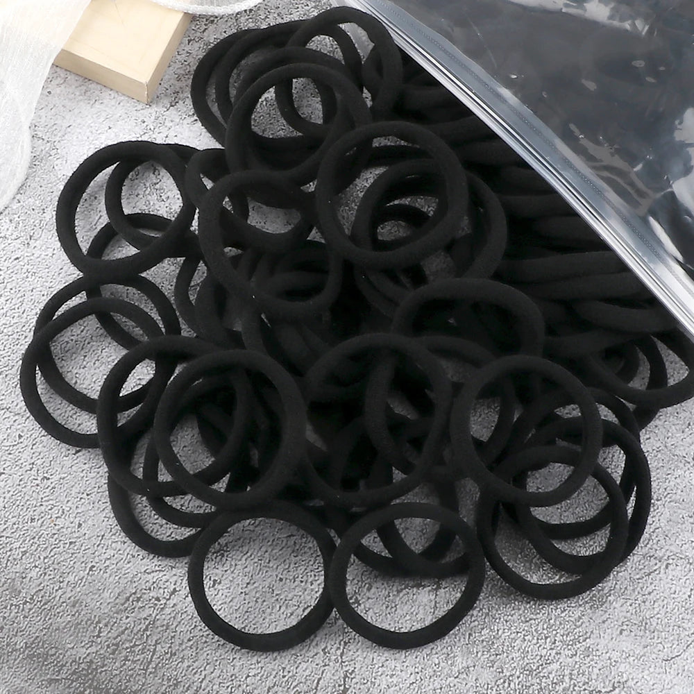 A pile of 50 pieces of mixed color elastic hair bands on a gray surface.