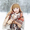 Una mujer usando una diadema de punto beige y una bufanda estampada al aire libre en la nieve.