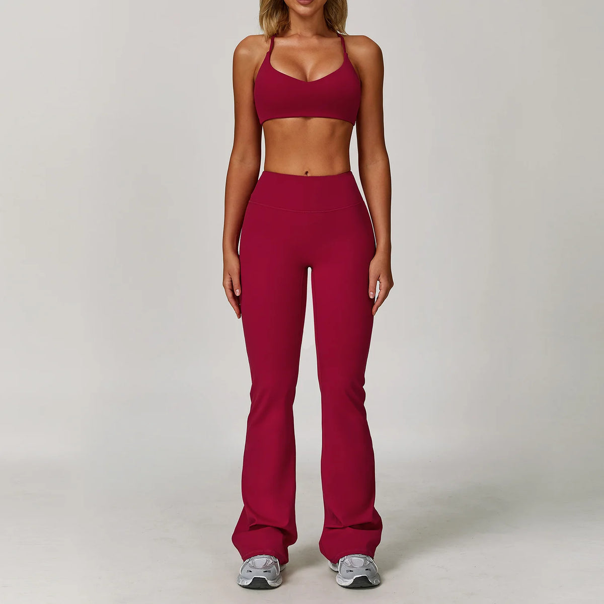 A woman models a maroon three-piece yoga sports set consisting of a cropped top and full-length leggings.