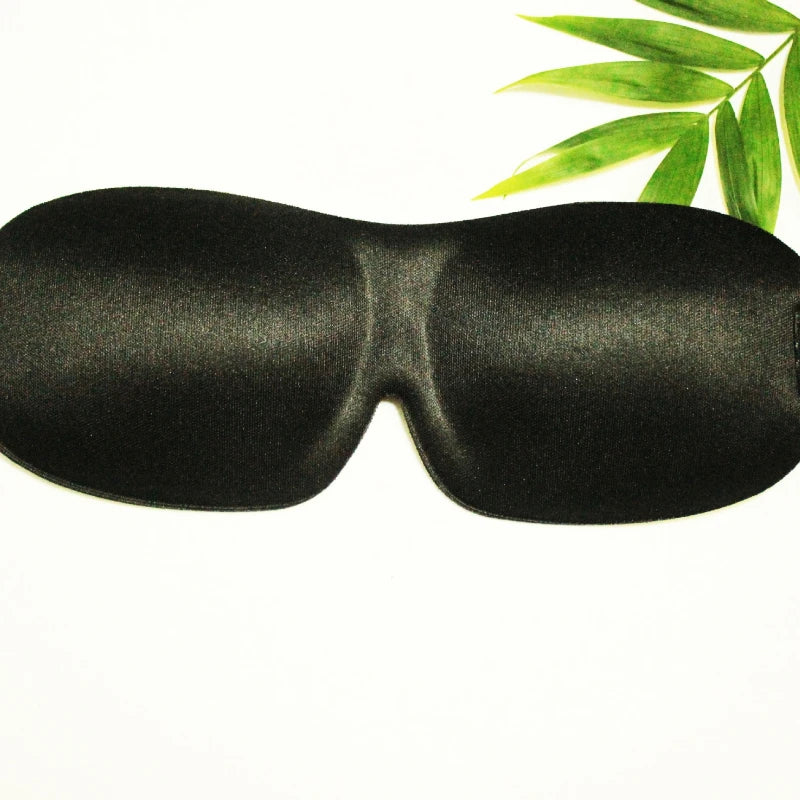 Black memory foam sleep mask with a green leaf in the background