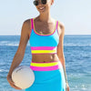 A woman wearing a color-block zigzag three-piece swimsuit set stands by the ocean.