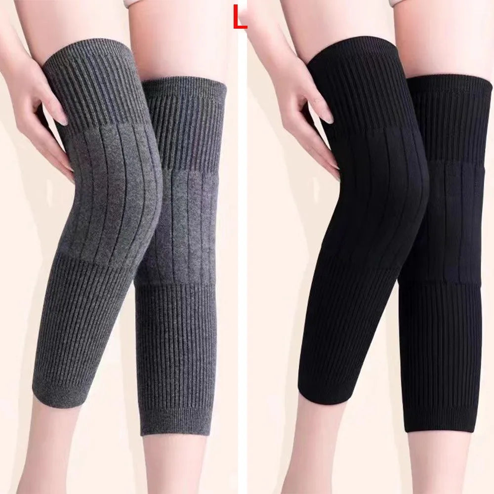 A pair of thick wool knee warmers in charcoal gray and black, shown on a model's legs.