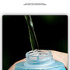 A hand holds a blue sports water bottle with a wide mouth design, pouring water into it.