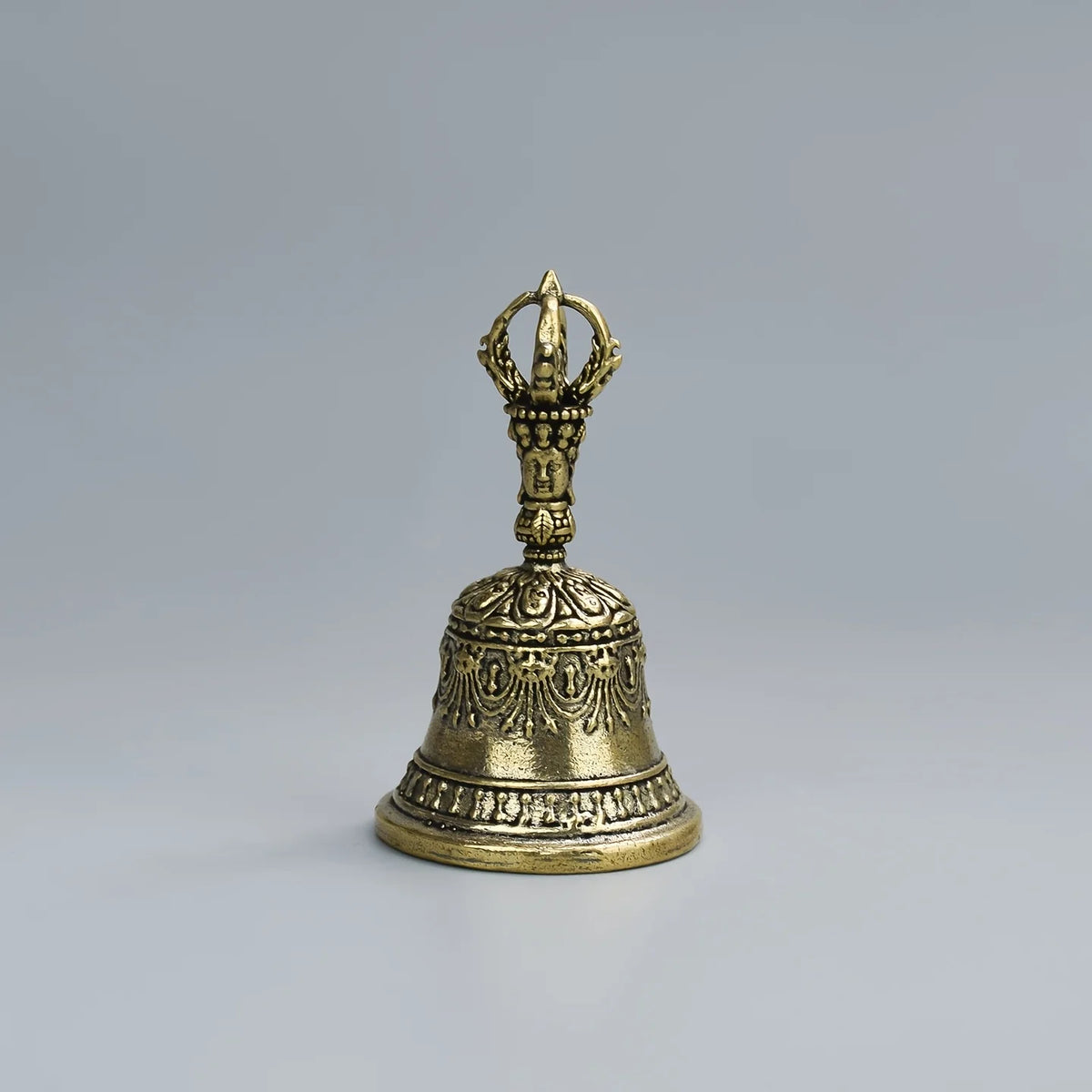 Cloche de bronze à tenir avec sommet orné et base évasée, utilisée pour la décoration spirituelle ou festive.