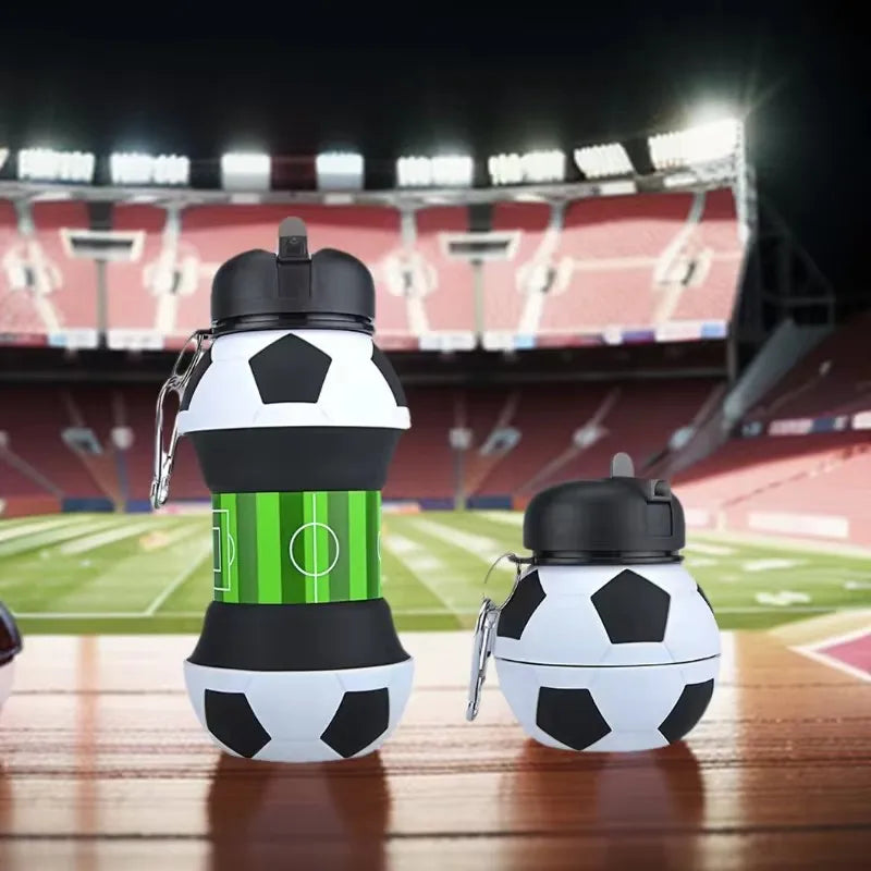 A white and black foldable silicone sports water bottle is shown next to a soccer ball on a wooden surface.