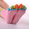 A pair of rainbow yoga socks with colorful toes and white polka dots on a foot.