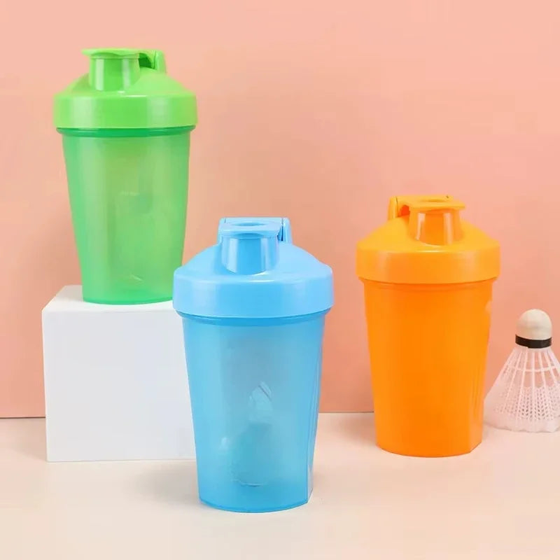 Three plastic sports bottles in green, blue, and orange colors standing on a white block.
