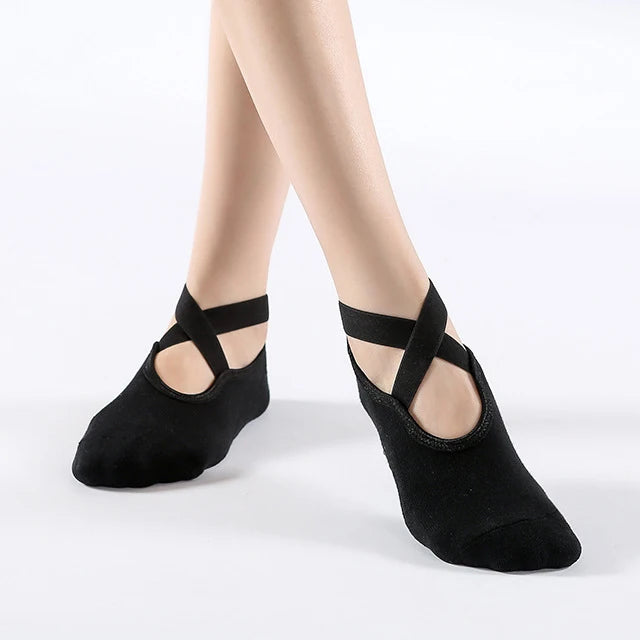 Black breathable silicone yoga and pilates socks worn on a person's feet.