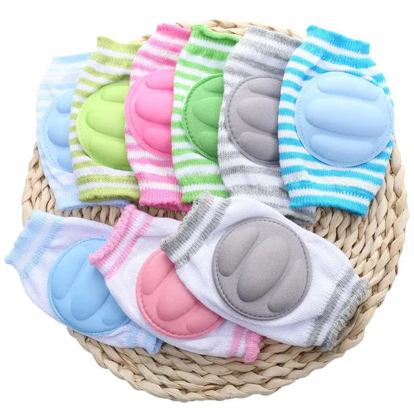 A collection of colorful toddler knee pads and leg warmers in various pastel shades are displayed on a woven mat.