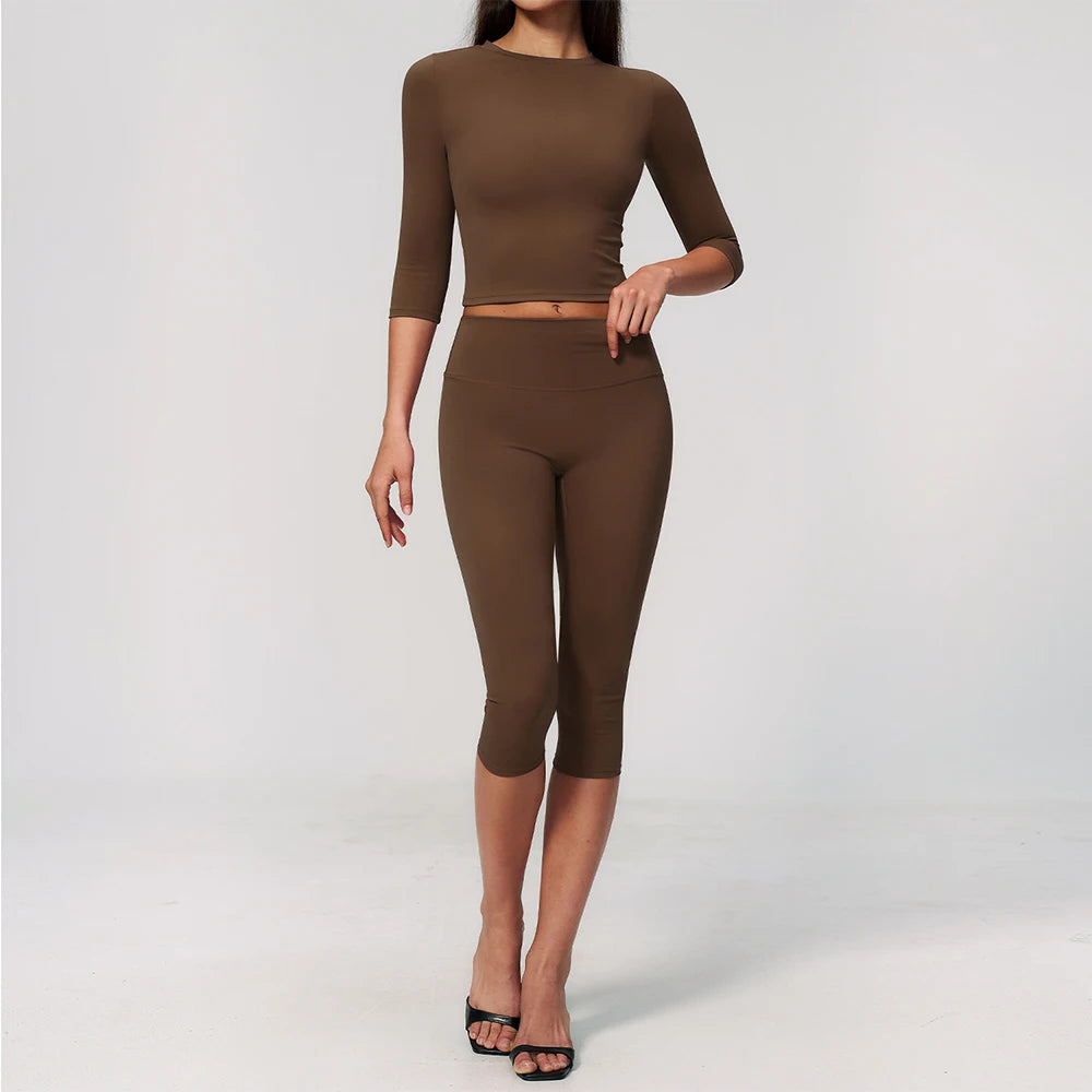 A woman wearing a matching olive brown long-sleeved top and leggings set for yoga or fitness.