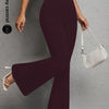 A model wearing dark plum flared yoga trousers and a white shoulder bag.
