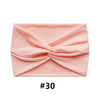 A pink fabric item folded into a criss-cross design, likely a boho wide turban headband.
