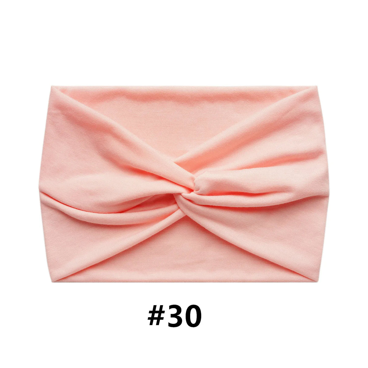 A pink fabric item folded into a criss-cross design, likely a boho wide turban headband.