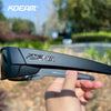 A close-up shot of black polarized sports sunglasses being held by a hand outdoors.