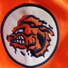 Rundes besticktes Patch mit stilisiertem braun-weißen Bärenkopf in orange und marineblau auf weißem Hintergrund, vor orangefa