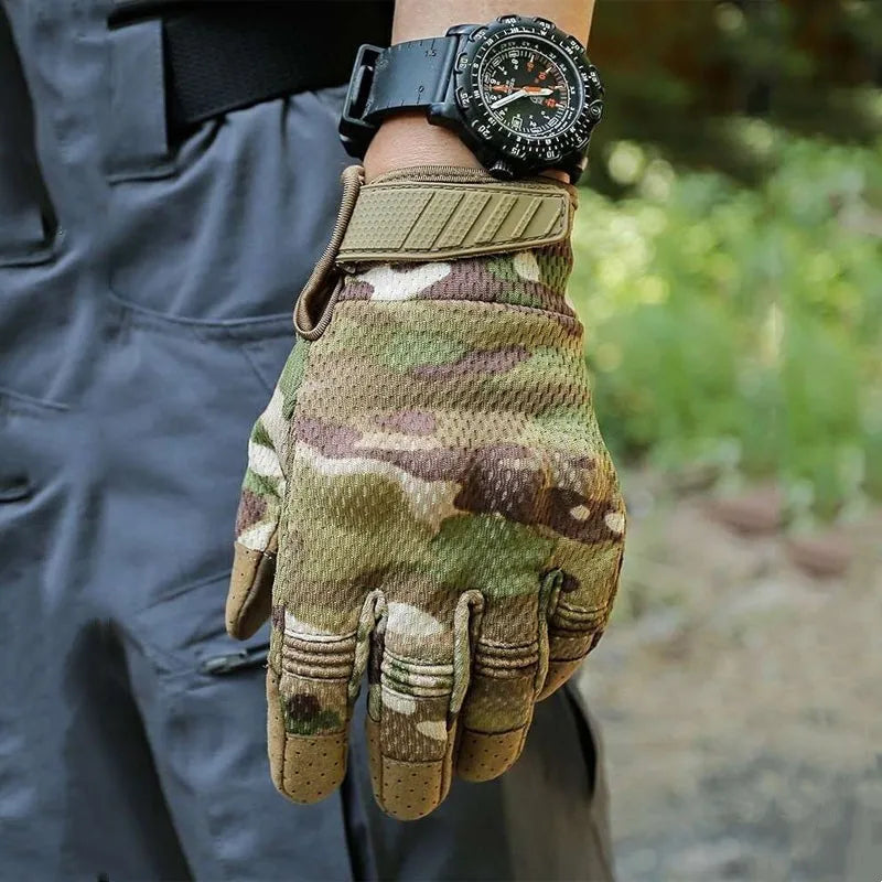 Une main portant des gants tactiques camouflage, avec une montre noire, tenue contre un vêtement sombre.