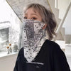 Una persona vistiendo una camisa negra de manga larga y una bufanda protectora UV con estampado paisley blanca cubriendo su c